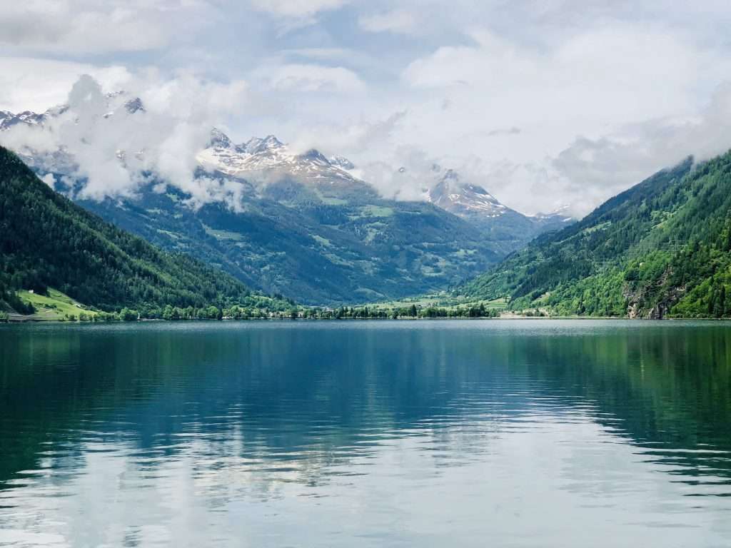 a photo of a lake with a snow capped mountain behind it