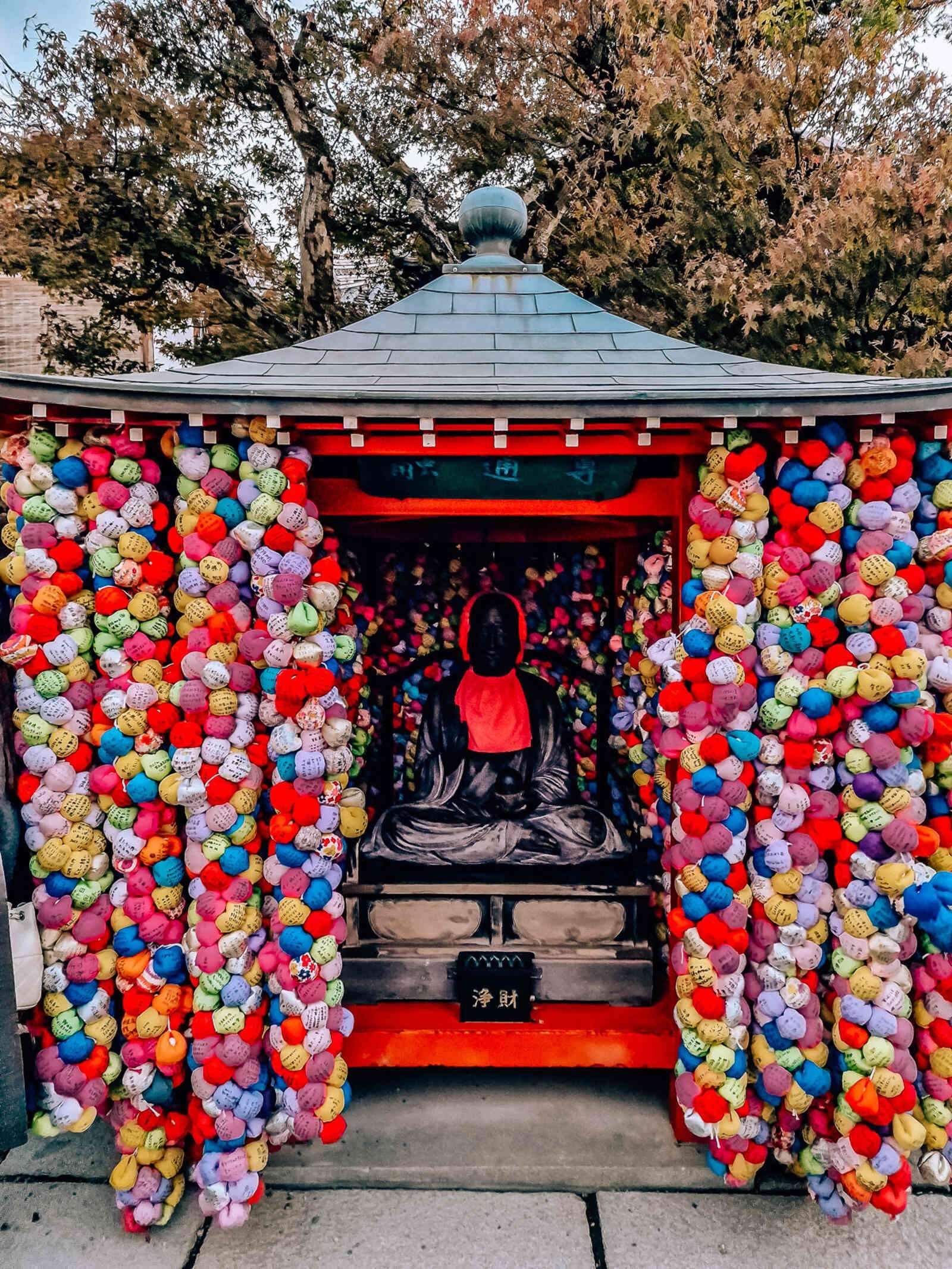 a small shrine covered in colourful cloth balls with writing on