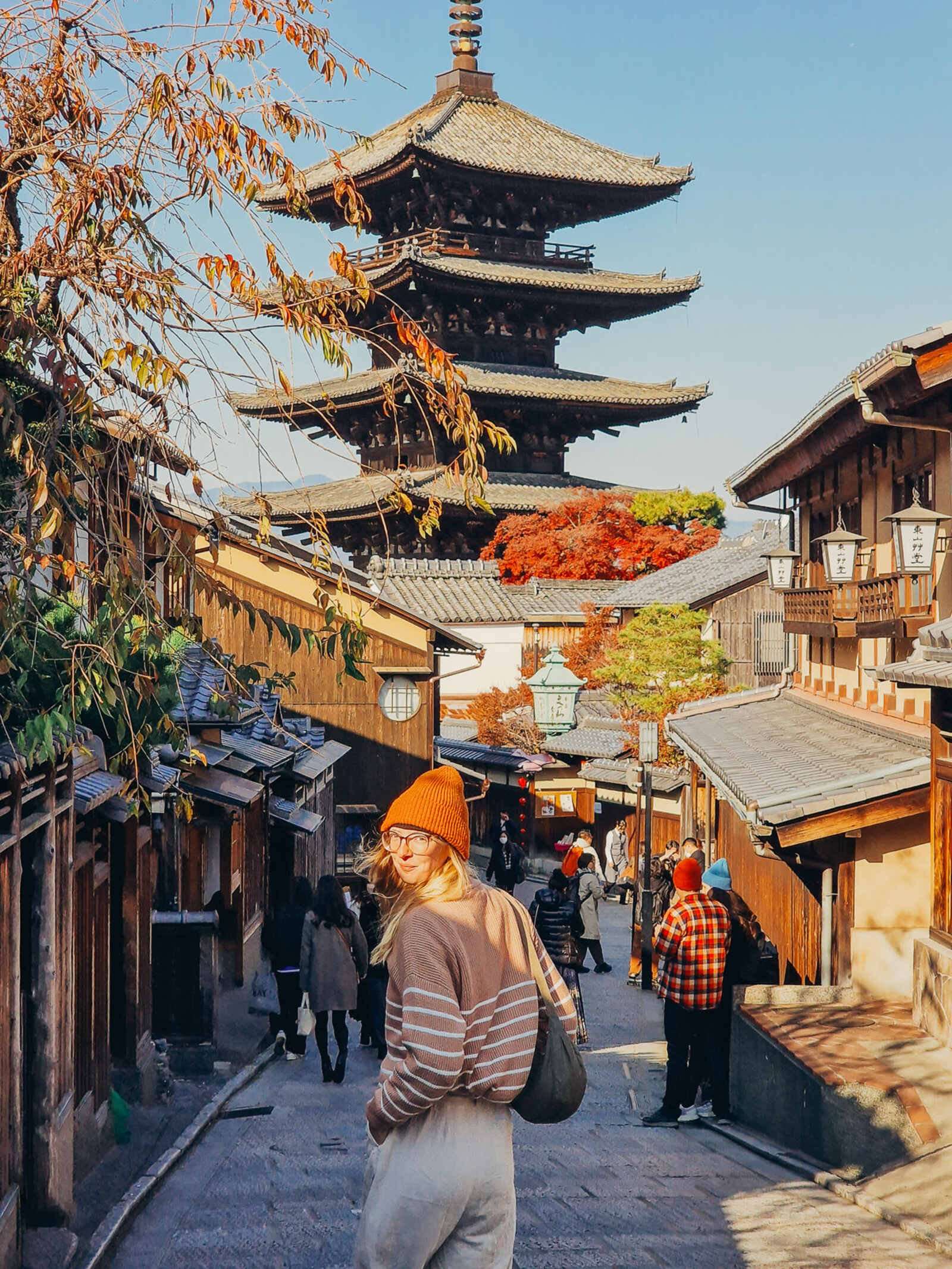 Helena turning towards the camera standing on a street in Kyoto with a pagoda in the background